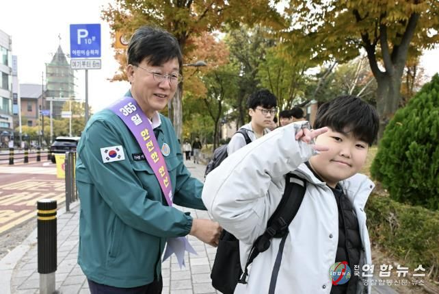 이민근 안산시장(사진 왼쪽)이 학현초등학교 앞에서 ‘스쿨존 어린이 교통안전 캠페인’을 진행하며 등교하는 어린이의 가방에 '홍이 키링'을 달아주고 있다.